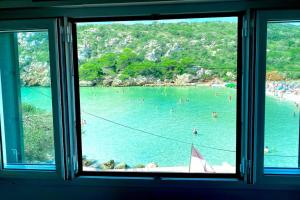 a window view of a beach with people in the water at Beachfront Apartment in Calan Porter Menorca in Cala en Porter