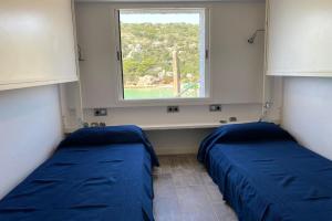 two beds in a room with a window at Beachfront Apartment in Calan Porter Menorca in Cala en Porter
