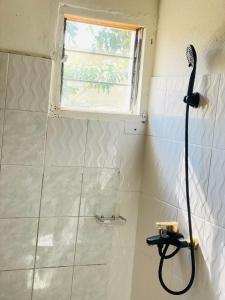 a shower with a hose in a bathroom with a window at Bulle d'Or Classique in Libreville