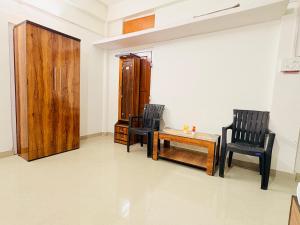 two black chairs and a table in a room at Kalm Homestay in Dispur