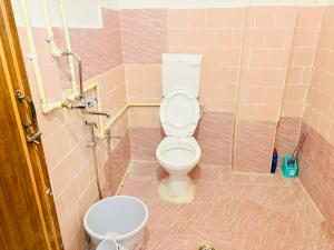 a bathroom with a toilet in a pink tiled bathroom at Kalm Homestay in Dispur