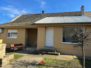 a house with a white door and a bench at Apartmani Centar in Sivac