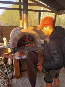 a man standing in front of a pizza oven at EcoPod Holidays in Alton