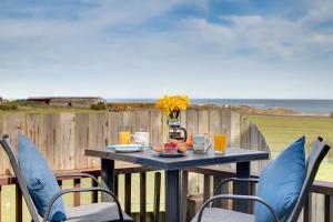 a table and chairs on a balcony with the ocean at Brackenrigg Embleton in Embleton