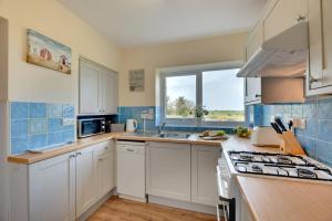 a kitchen with white cabinets and a sink and a window at Brackenrigg Embleton in Embleton