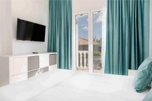 a white bedroom with a television and a large window at Villa Mika in Zakynthos