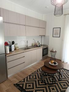 a kitchen with white cabinets and a table and a sink at Antoine Apartment in Nea Peramos +14 photos