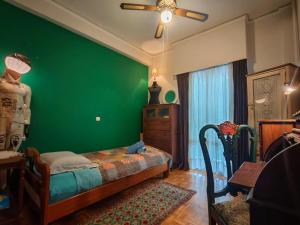 a bedroom with a green wall with a bed and a dresser at Retro private room in common apartment in Athens
