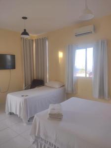 a hotel room with two beds and a window at Suíte prime in Monte das Gameleiras