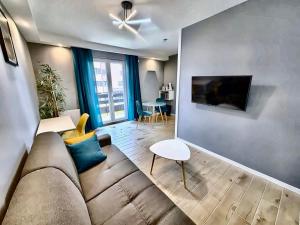 a living room with a couch and a tv at Le Genev Altitude - Studio Lumineux - Vue Montagne in Collonges-sous-Salève +2 photos