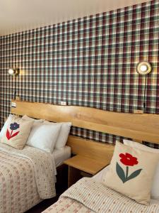 a bedroom with two beds and a plaid wall at Auberge du Jardin in Petit-Saguenay