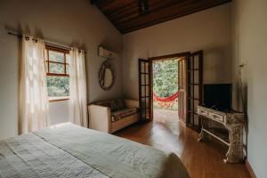 a bedroom with a bed and a chair and a window at Hotel Solar Fazenda Do Cedro in Itaipava