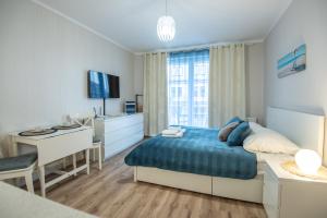 a bedroom with a bed and a desk and a television at Apartamenty na Wyspie - Villa Pegaz - Parking in Świnoujście