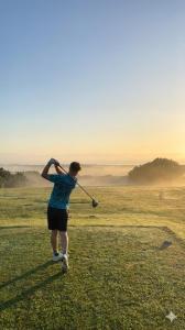 a man swinging a golf club on a golf course at Mtunzini Rustic Retreat in Mtunzini