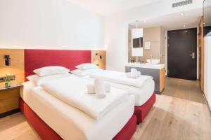 two beds in a hotel room with a bathroom at Best Western Hotel Tulln in Tulln