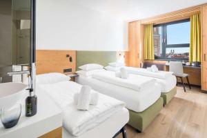 a row of white beds in a room with a window at Best Western Hotel Tulln in Tulln