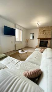 a room with three white beds and a fireplace at Le Gite Zoé in Bourbourg