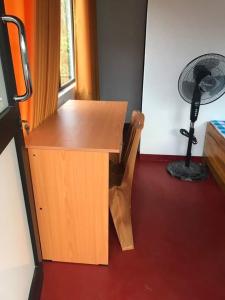 a wooden desk with a fan in a room at 5th Dimension Academy rooms in Deniyaya