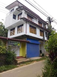 a white building with a blue garage in front of it at 5th Dimension Academy rooms in Deniyaya