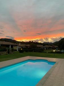 a blue swimming pool with a sunset in the background at Villino Giò - Residence Abba Urci in Tertenìa