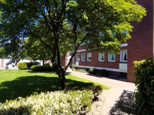 a tree in a yard next to a brick building at Ferienwohnung "Erika" Rees am Niederrhein in Rees