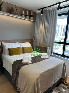 a large bed in a room with a large window at Studio perto Shopping Estação com Piscina interna aquecida, Academia e Terraço Lindo pôr do Sol in Curitiba +10 photos