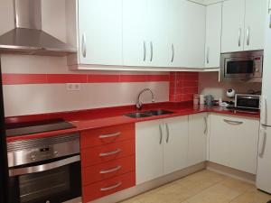 a kitchen with red and white cabinets and a sink at Casa Lili in Vélez-Rubio