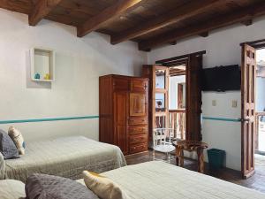 a bedroom with two beds and a television in a room at Patio Guadalupe in San Cristóbal de Las Casas