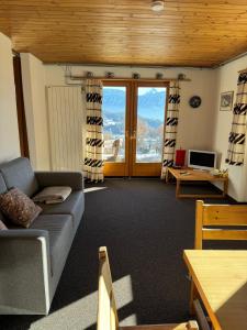 a living room with a couch and a table and a television at Chalet Heide Beatenberg in Beatenberg