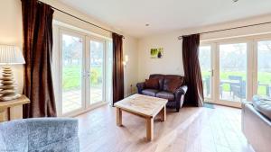 a living room with a leather chair and a table at Meadow Shores - Part of the The Bay Filey Holiday Village with pool, gym and direct beach access, pub, restaurant, tennis and meadows walks in Filey