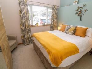 a bedroom with a bed with a yellow blanket at Blake Lodge in Newquay