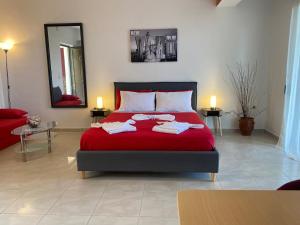 a bedroom with a red bed with towels on it at Aristos Apartments & Suites in Stalos