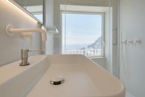 a white bathroom with a sink and a window at Sopramonte Exclusive Rooms in Capri +79 photos