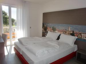 Cama en habitación con ventana grande en Residence Rivachiara (check-in at Hotel Riviera in Viale Rovereto, 95), en Riva del Garda