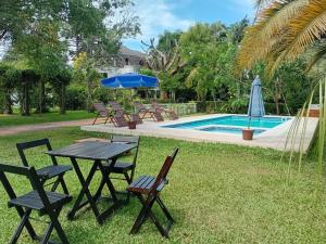 a picnic table and chairs next to a pool at ROSA CORTIANA Escalera in São Gabriel