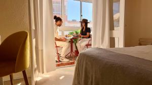 a man and woman sitting at a table in a room at Refúgio na Praia de Santa Cruz- A poucos passos da praia, surf e restaurantes in Santa Cruz