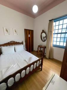 a bedroom with a large bed and a window at Hotel Lenheiros in São João del Rei