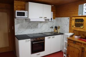 a kitchen with white cabinets and a stove top oven at Ferienhaus Fernblick in Fraxern