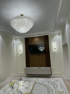 a living room with a chandelier and a tv at Asolat house in Urganch