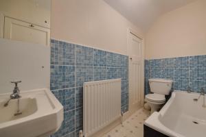 a blue tiled bathroom with a sink and a toilet at 2 Bed in Warkworth oc-nb319 in Warkworth