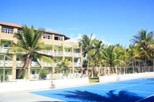 una pista de tenis frente a un hotel con palmeras en Mar & Sol Praia Hotel en Prado