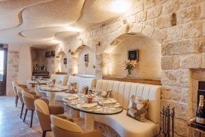a restaurant with tables and chairs and a stone wall at Via Regia Cappadocia Hotel in Uçhisar