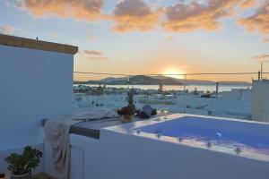 a hot tub on the roof of a building with the sunset at Kalypso Vacation Home Naxos Town in Naxos Chora