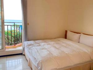 a bedroom with a bed and a balcony at Captain's Homestay in Baisha