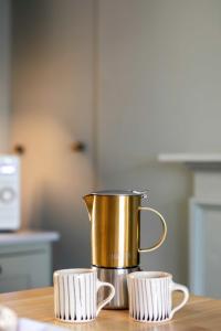 a gold coffee pot on a table with two cups at Old Orchard Elegance - Private Parking in Bath
