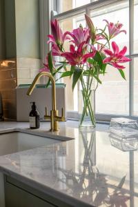a vase of pink flowers sitting on a kitchen counter at Old Orchard Elegance - Private Parking in Bath +19 photos