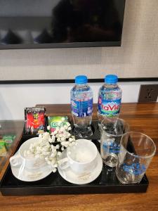 a tray with two bottles of water and plates and glasses at Lâm Luxury Hotel Lào Cai in Chơ Mơi