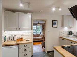 a kitchen with white cabinets and a living room at 2 Bed in Keswick oc-90064 in Threlkeld