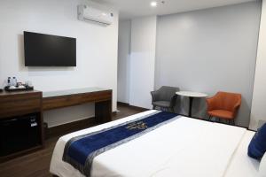 a hotel room with a bed and a desk and a tv at Lâm Luxury Hotel Lào Cai in Chơ Mơi