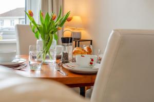 a table with a vase of tulips and a plate of food at 3 Bed in Padstow oc-p00131 in Saint Merryn